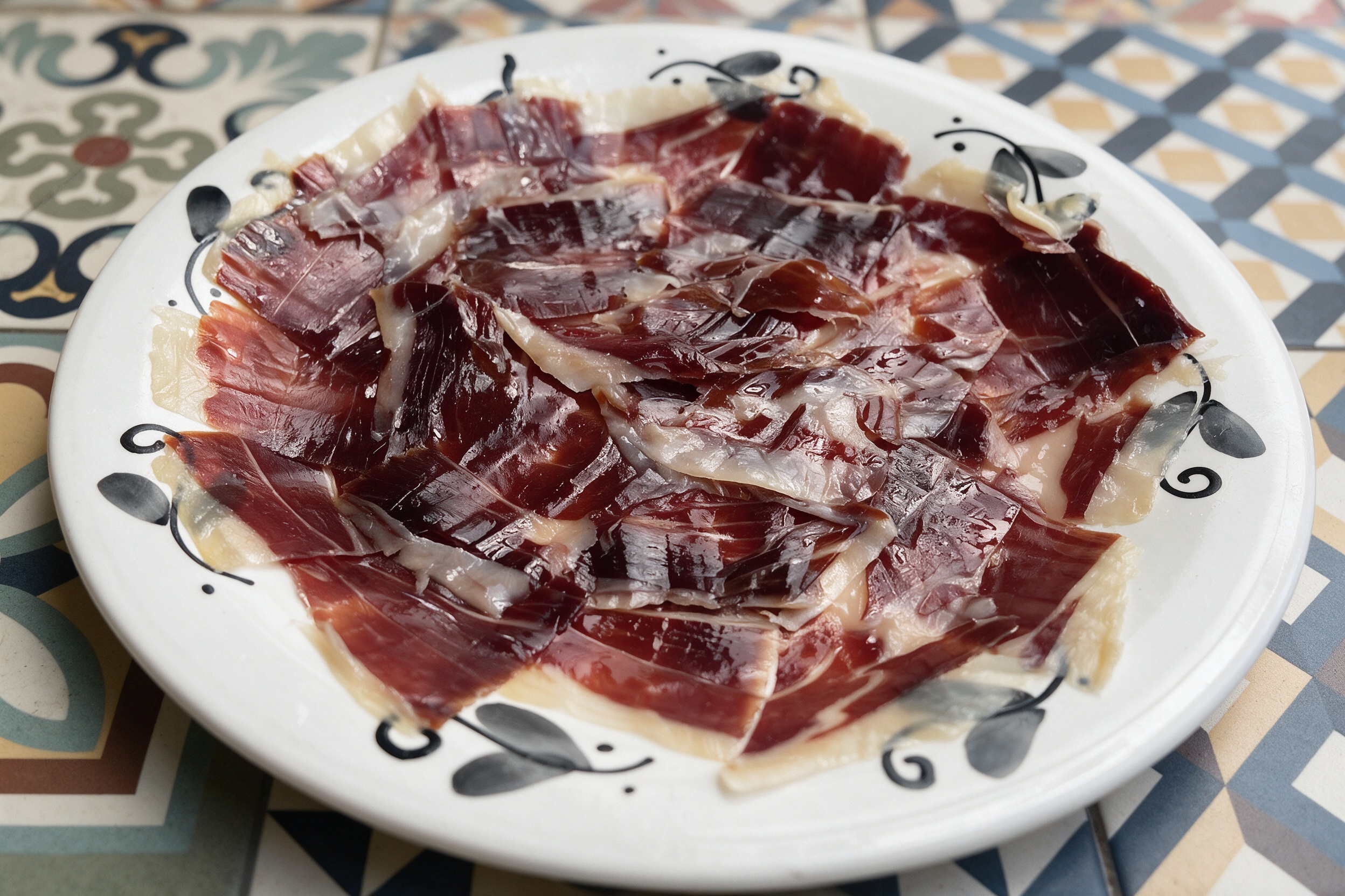 Jamón ibérico de bellota — lonchas finas sobre plato blanco